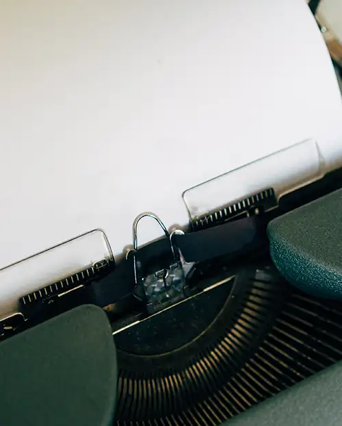 A typewriter ready with a blank sheet of paper in it.